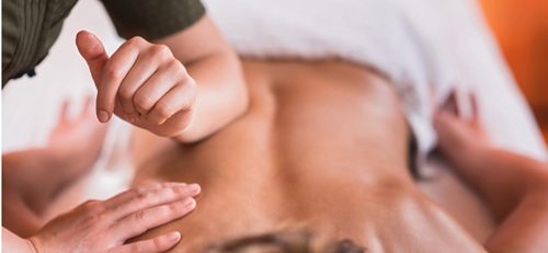 Close up of someone laying on their front being given a back massage